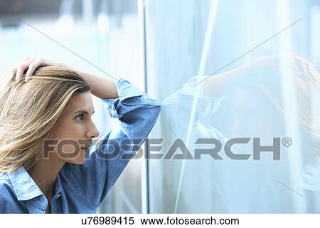 Mid adult businesswoman leaning against glass wall in office with hand in hair View Large Photo Image Stock Photography - Mid adult businesswoman leaning against glass wall in office with hand in hair. Fotosearch