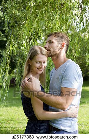 Stock Photo - Mid adult couple embracing in garden. Fotosearch