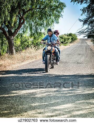 Mid adult couple riding motorcycle on rural road, Cagliari, Sardinia, Italy View Large Photo Image Stock Image - Mid adult couple riding motorcycle on rural road, Cagliari, Sardinia, Italy. Fotosearch