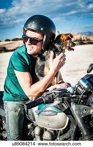 Mid adult man and dog sitting on motorcycle on arid plain, Cagliari, Sardinia, Italy View Large Photo Image Picture - Mid adult man and dog sitting on motorcycle on arid plain, Cagliari, Sardinia, Italy. Fotosearch