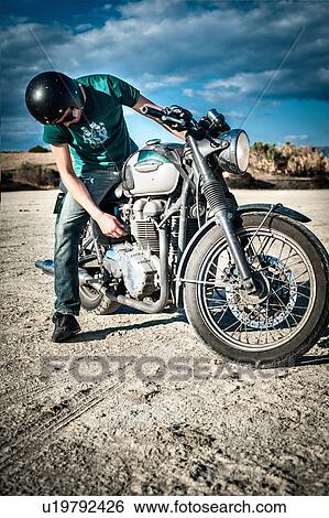 Mid adult man checking motorcycle on arid plain, Cagliari, Sardinia, Italy View Large Photo Image Stock Photograph - Mid adult man checking motorcycle on arid plain, Cagliari, Sardinia, Italy. Fotosearch