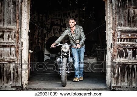 Mid adult man pushing motorcycle out of barn doorway View Large Photo Image Stock Photo - Mid adult man pushing motorcycle out of barn doorway. Fotosearch