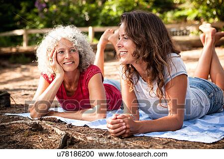 Stock Image - Mother and daughter on picnic blanket by the Blue Pool, Wareham, Dorset, United Kingdom. Fotosearch
