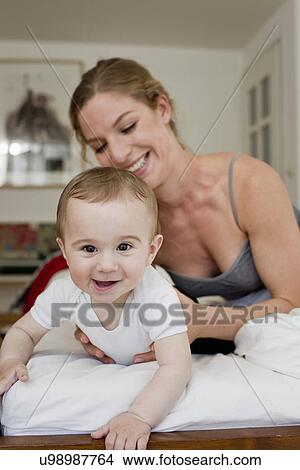 Mother guiding baby boy crawling on bed View Large Photo Image Picture - Mother guiding baby boy crawling on bed. Fotosearch