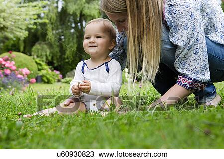 Mother with baby girl sitting on grass View Large Photo Image Stock Image - Mother with baby girl sitting on grass. Fotosearch