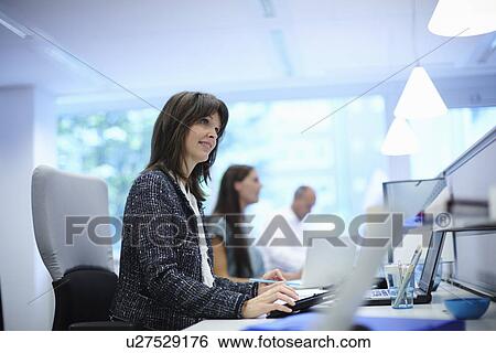 Office workers at their desks in busy office View Large Photo Image Stock Photograph - Office workers at their desks in busy office. Fotosearch