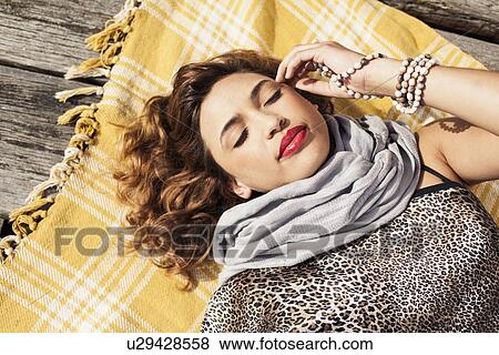 Stock Photo - Overhead view of glamorous young woman with eyes closed on pier. Fotosearch