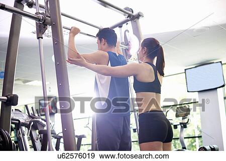 Personal trainer helping young man lift weights View Large Photo Image Stock Photo - Personal trainer helping young man lift weights. Fotosearch
