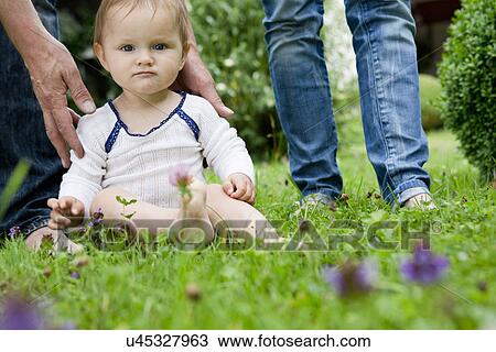 Stock Image - Portrait of baby girl sitting on lawn staring. Fotosearch