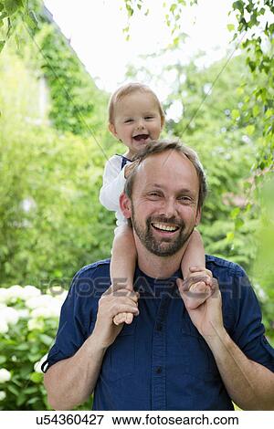 Portrait of baby girl sitting on fathers shoulders in garden View Large Photo Image Stock Photo - Portrait of baby girl sitting on fathers shoulders in garden. Fotosearch