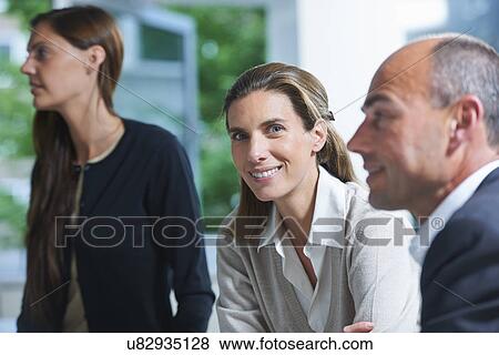 Stock Photo - Portrait of businesswoman between colleagues in office. Fotosearch