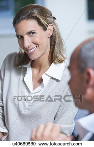 Stock Image - Portrait of businesswoman next to colleague in office. Fotosearch
