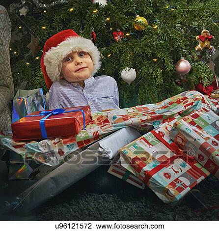 Portrait of cute boy sitting on floor with christmas presents on top of him View Large Photo Image Stock Image - Portrait of cute boy sitting on floor with christmas presents on top of him. Fotosearch