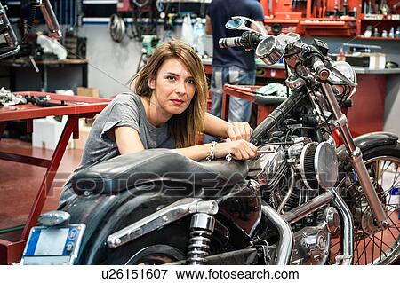 Stock Photo - Portrait of female mechanic in motorcycle workshop. Fotosearch