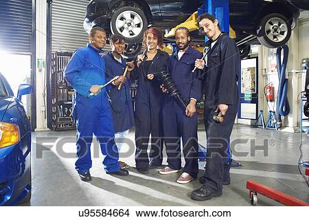 Picture - Portrait of five college students beneath car in garage workshop. Fotosearch