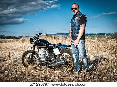 Stock Photo - Portrait of male motorcyclist in plain landscape, Cagliari, Sardinia, Italy. Fotosearch