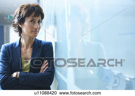 Portrait of mature businesswoman leaning against glass wall with arms crossed View Large Photo Image Stock Image - Portrait of mature businesswoman leaning against glass wall with arms crossed. Fotosearch
