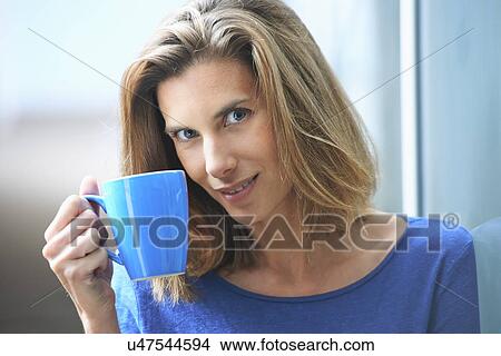 Portrait of mid adult businesswoman leaning against glass wall drinking coffee View Large Photo Image Picture - Portrait of mid adult businesswoman leaning against glass wall drinking coffee. Fotosearch