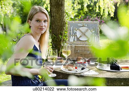 Portrait of mid adult woman sitting at picnic table with a glass of white wine in garden View Large Photo Image Stock Image - Portrait of mid adult woman sitting at picnic table with a glass of white wine in garden. Fotosearch