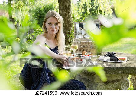 Portrait of mid adult woman sitting at picnic table in garden View Large Photo Image Stock Photo - Portrait of mid adult woman sitting at picnic table in garden. Fotosearch