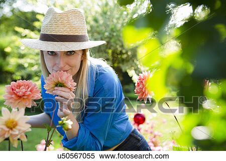 Stock Photography - Portrait of mid adult woman smelling garden blooms. Fotosearch