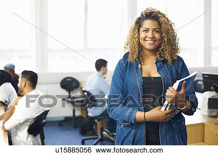 Stock Photograph - Portrait of teenage female student with file in college classroom. Fotosearch