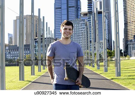 Stock Photography - Portrait of young man holding skateboard. Fotosearch
