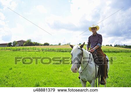 Portrait of young man in cowboy gear on horseback in field View Large Photo Image Stock Photo - Portrait of young man in cowboy gear on horseback in field. Fotosearch