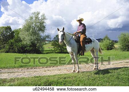 Portrait of young man in cowboy gear on horseback on dirt track View Large Photo Image Stock Photo - Portrait of young man in cowboy gear on horseback on dirt track. Fotosearch