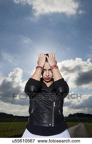 Stock Photo - Portrait of young woman on rural road with head in hands. Fotosearch