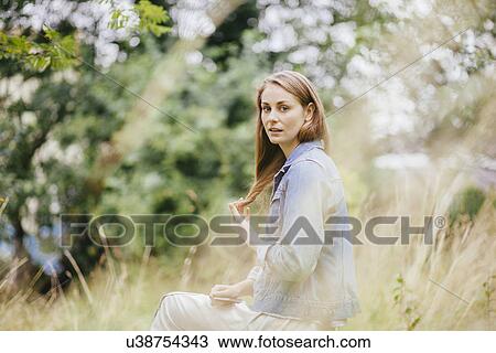 Portrait of young woman with hand in hair in field View Large Photo Image Stock Image - Portrait of young woman with hand in hair in field. Fotosearch
