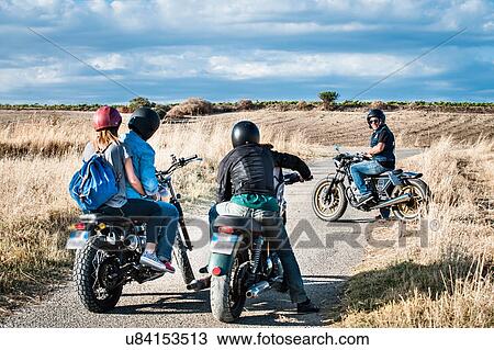 Rear view of four friends chatting on motorcycles on rural road, Cagliari, Sardinia, Italy View Large Photo Image Stock Image - Rear view of four friends chatting on motorcycles on rural road, Cagliari, Sardinia, Italy. Fotosearch