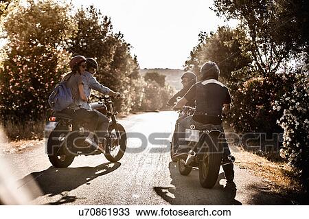 Rear view of four friends on motorcycles chatting on rural road, Cagliari, Sardinia, Italy View Large Photo Image Stock Image - Rear view of four friends on motorcycles chatting on rural road, Cagliari, Sardinia, Italy. Fotosearch