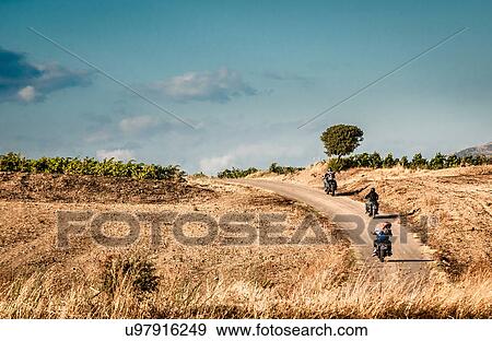 Rear view of four friends riding motorcycles on rural road, Cagliari, Sardinia, Italy View Large Photo Image Stock Photo - Rear view of four friends riding motorcycles on rural road, Cagliari, Sardinia, Italy. Fotosearch
