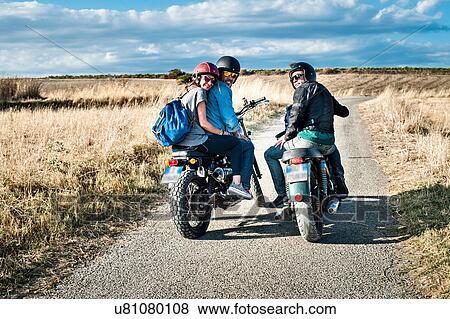 Stock Photo - Rear view of three friends on motorcycles on rural road, Cagliari, Sardinia, Italy. Fotosearch
