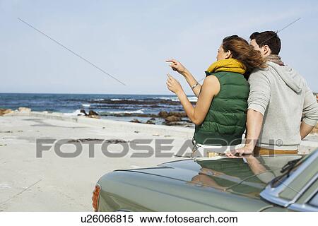 Rear view of young couple leaning against car at coast, Cape Town, Western Cape, South Africa View Large Photo Image Stock Photography - Rear view of young couple leaning against car at coast, Cape Town, Western Cape, South Africa. Fotosearch