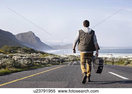 Rear view of young man with guitar case walking on coastal road, Cape Town, Western Cape, South Africa View Large Photo Image Stock Photography - Rear view of young man with guitar case walking on coastal road, Cape Town, Western Cape, South Africa. Fotosearch