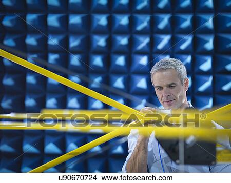 Scientist preparing to measure electromagnetic waves in anechoic chamber, close up View Large Photo Image Picture - Scientist preparing to measure electromagnetic waves in anechoic chamber, close up. Fotosearch