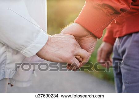 Picture - Senior couple holding hands, close up. Fotosearch