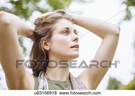 Serene young woman gazing up with hands in hair View Large Photo Image Stock Photo - Serene young woman gazing up with hands in hair. Fotosearch