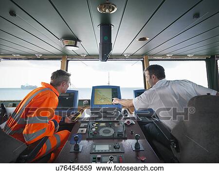 Stock Photo - Ship worker and captain inspecting radar on ship at sea. Fotosearch