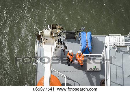 Stock Image - Ship's captain and worker on deck of container ship, overhead view. Fotosearch