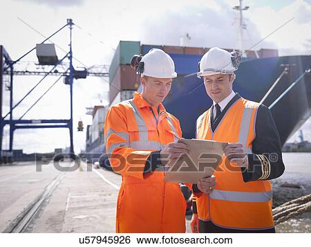 Stock Photograph - Ship's captain discussing loading cargo with port worker. Fotosearch