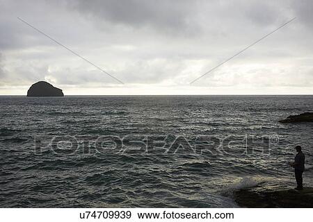 Stock Photo - Silhouetted man sea fishing from rock, Treknow, Cornwall, UK. Fotosearch