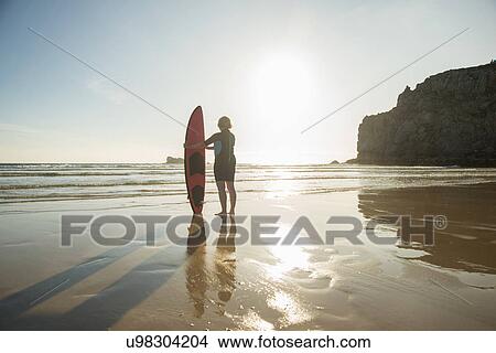 Silhouetted senior woman standing on beach with surfboard, Camaret-sur-mer, Brittany, France View Large Photo Image Picture - Silhouetted senior woman standing on beach with surfboard, Camaret-sur-mer, Brittany, France. Fotosearch