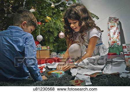 Sister and brother in sitting room unwrapping christmas gifts View Large Photo Image Stock Photo - Sister and brother in sitting room unwrapping christmas gifts. Fotosearch