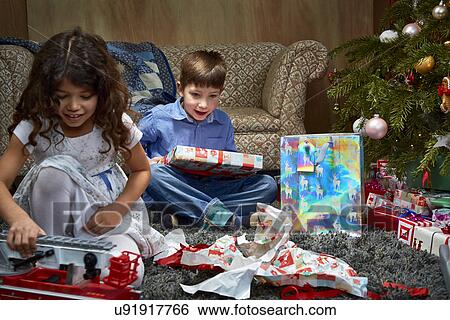 Sister and brother in sitting room unwrapping and playing with christmas gifts View Large Photo Image Stock Photograph - Sister and brother in sitting room unwrapping and playing with christmas gifts. Fotosearch