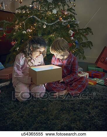 Sister and brother open mouthed on unwrapping glowing christmas gift box View Large Photo Image Stock Photography - Sister and brother open mouthed on unwrapping glowing christmas gift box. Fotosearch