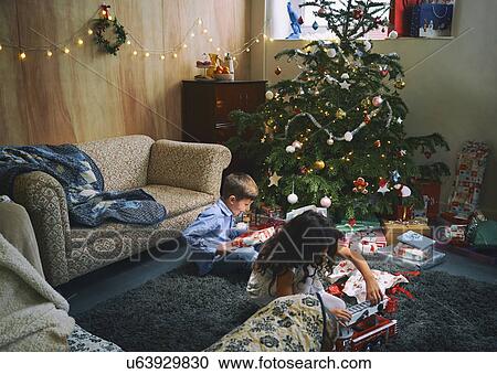 Sister and brother playing with and unwrapping christmas gifts on sitting room floor View Large Photo Image Stock Image - Sister and brother playing with and unwrapping christmas gifts on sitting room floor. Fotosearch