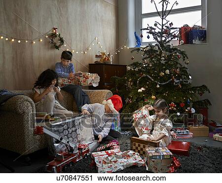 Sisters and brothers opening christmas gifts in sitting room View Large Photo Image Stock Image - Sisters and brothers opening christmas gifts in sitting room. Fotosearch